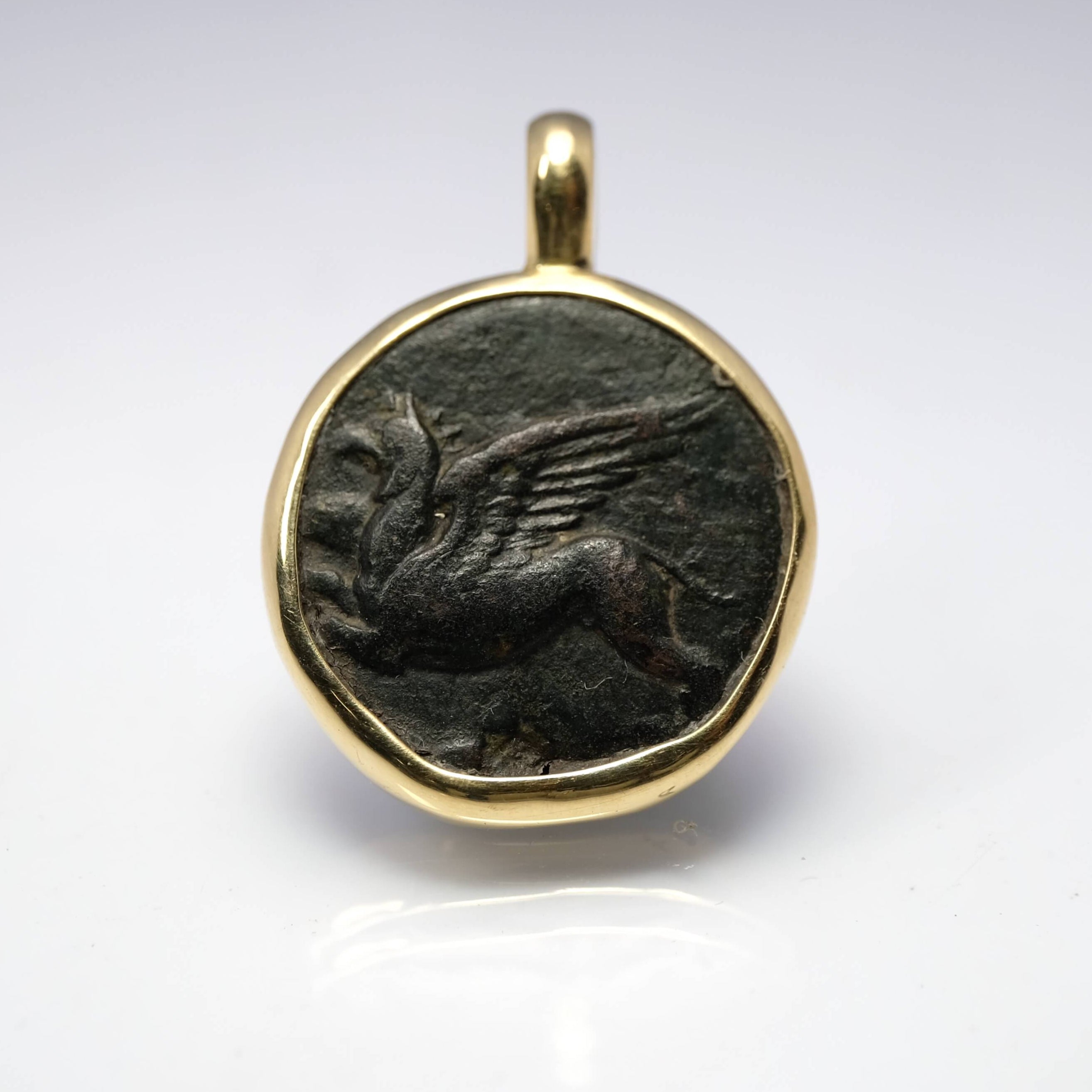 Pendant with a winged creature design on a white background
